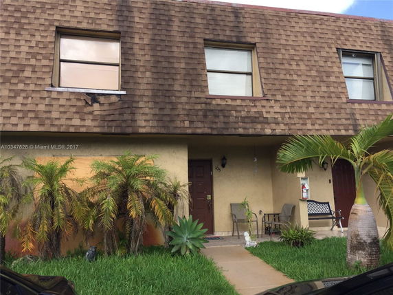 Front view of a two-story townhouse with a brown shingled roof.