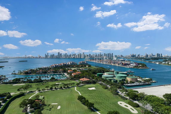 Panoramic view of a coastal city skyline, golf course, and harbor.