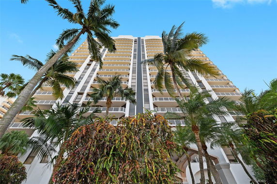 Front view of a high-rise building with multiple balconies and palm trees.