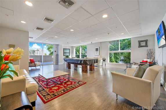 Interior of a recreation room with a pool table, seating area, and large windows.