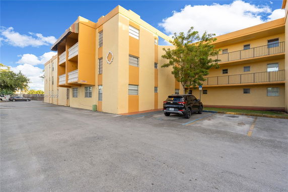 Front view of a multi-story apartment building with parking spaces.