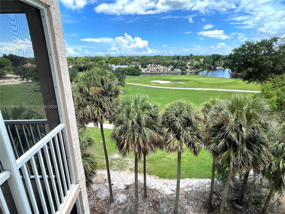 View from a building overlooking a green landscape with trees and a pond.