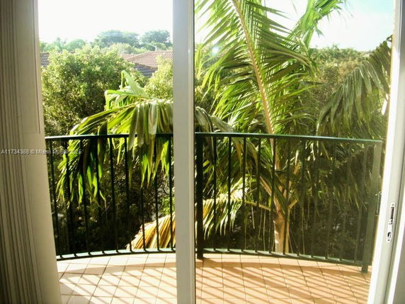 View of surrounding trees and foliage from a balcony with glass doors.