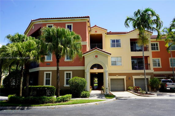 Front view of a multi-story residential building with an arched entrance and multiple garage doors.