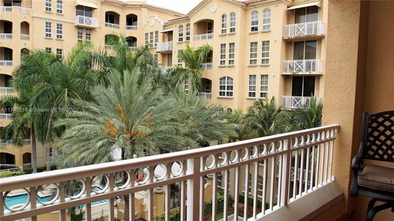 View from a balcony showing a multi-story residential building and palm trees.
