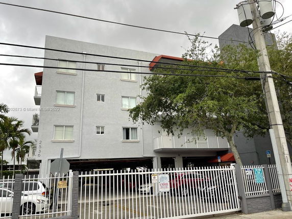 Front view of a multi-story residential building with a gated parking area.