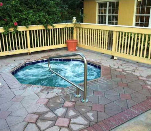 Outdoor area with a small hot tub surrounded by a deck with railing.