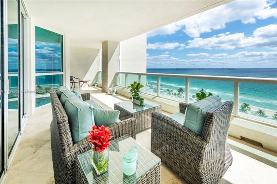 Balcony with wicker furniture overlooking the ocean and beach.