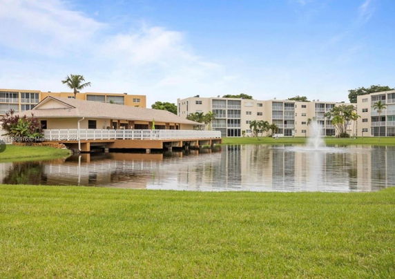View of apartment buildings with a pond and fountain in the foreground.