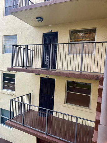 Exterior view of a multi-story building with balconies and unit doors.