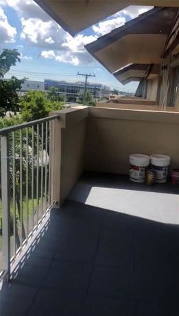 Balcony view overlooking nearby buildings and trees.