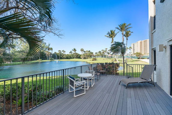 Outdoor deck area overlooking a water body and surrounding palm trees.
