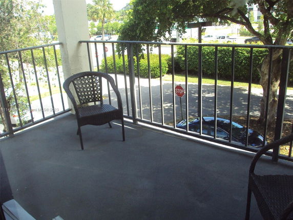 Outdoor balcony area with a view of the street and trees.
