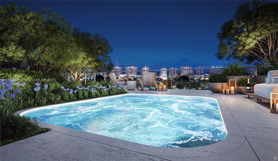 Rooftop view featuring a jacuzzi or pool, surrounded by chairs and plants with a cityscape in the background at night.