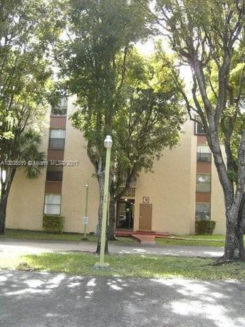 Front view of a multi-story apartment building with trees around.