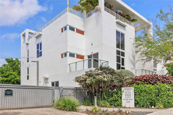 Front view of a modern multi-story building with a gated entrance.