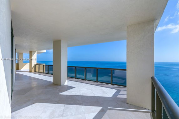 View of ocean from a large balcony with glass railings.