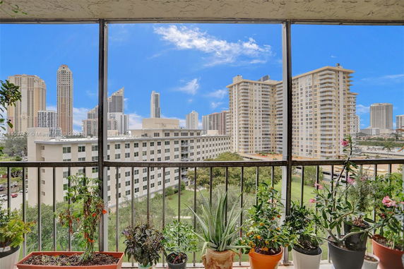 View of surrounding skyscrapers from a balcony with potted plants.