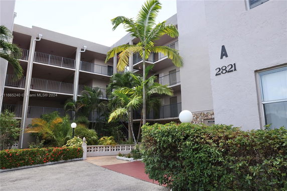 Front view of a multi-story building with balconies and a number on the facade.