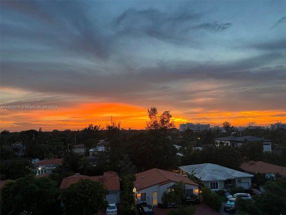 A panoramic view of a suburban area with houses and a vibrant sunset in the background.