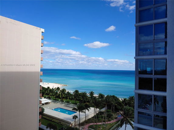 View from a building overlooking a beach and the ocean, with nearby structures visible.