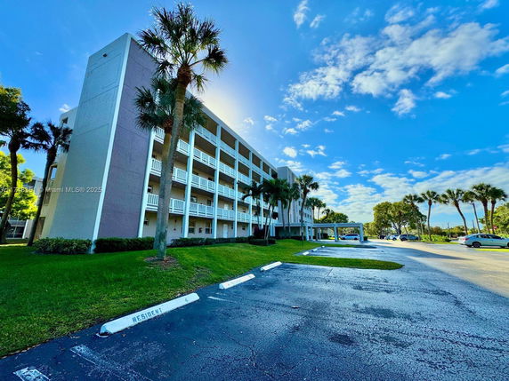 Front view of a multi-story building with balconies and surrounding landscape.