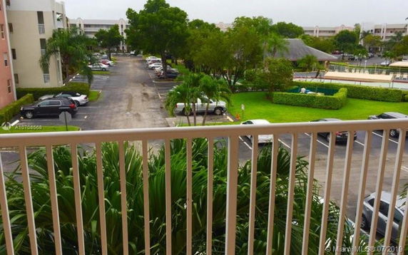 View from a balcony overlooking a parking area and surrounding greenery.