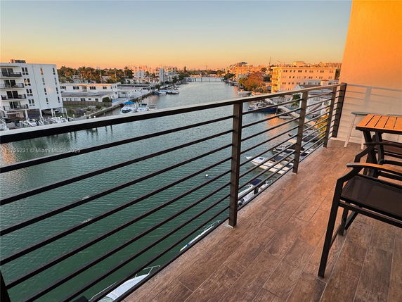 View from a balcony overlooking a waterway with buildings and boats below.