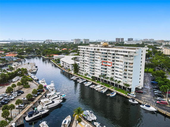 Elevated view of a multi-story residential building along a waterway with boats docked nearby.