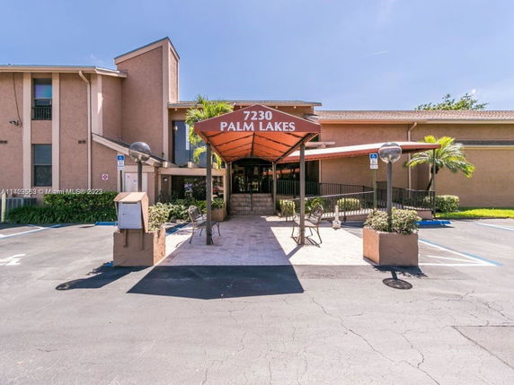 Front view of a multi-story building with a covered entrance and parking area.