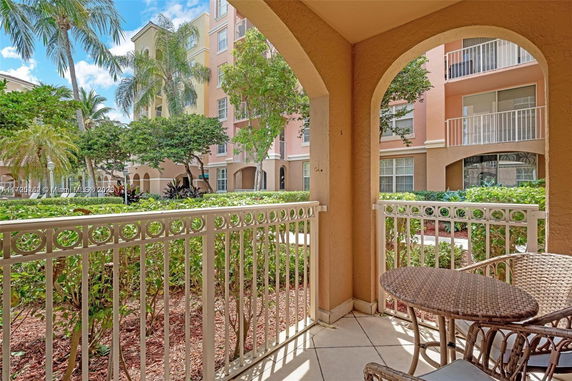 View from a balcony overlooking a garden and multi-story residential buildings with arched windows.