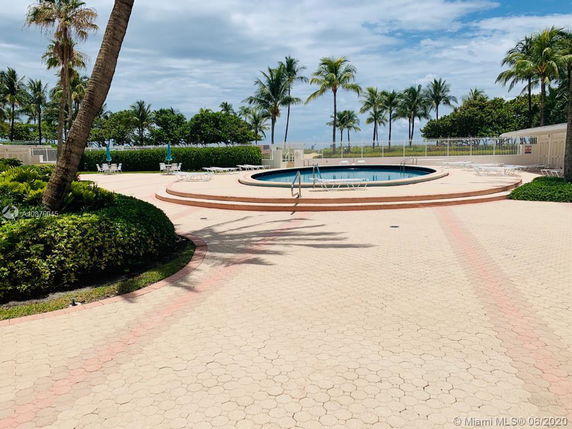 Outdoor swimming pool area with palm trees and tiled surroundings.