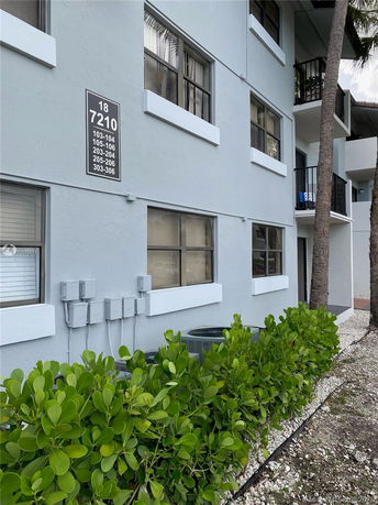 Side view of a multi-story residential building with balconies and air conditioning units.