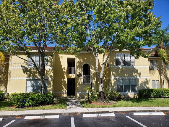Front view of a two-story apartment building with yellow exterior and a central entrance.