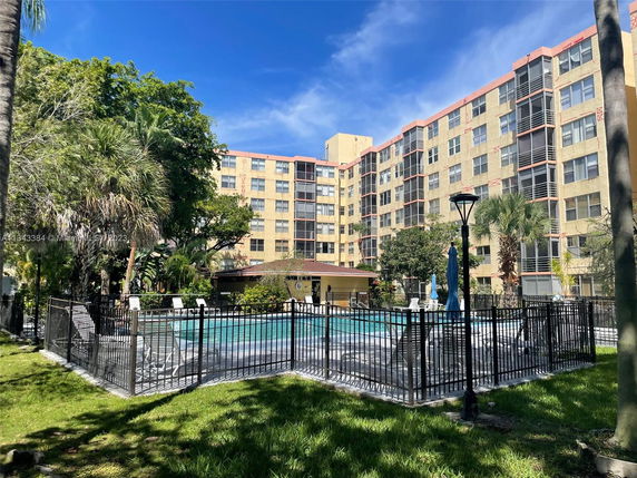 Outdoor swimming pool area in front of a multi-story residential building.