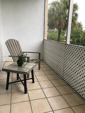 Balcony with a chair and table overlooking trees