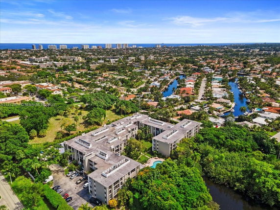 Panoramic view of a residential area with a cluster of buildings and lush greenery, extending towards the distant city skyline and ocean.