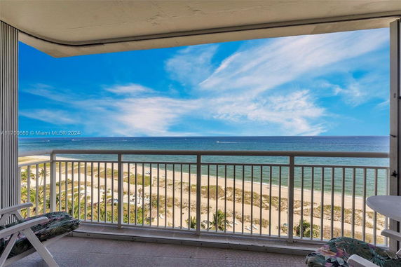 Panoramic view of the ocean and sandy beach from a building balcony.