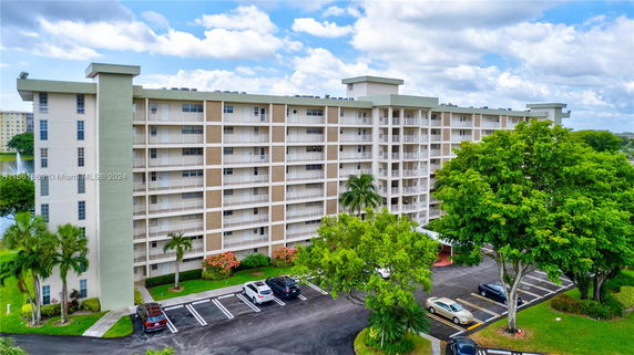Front view of a multi-story residential building with balconies and parking area.
