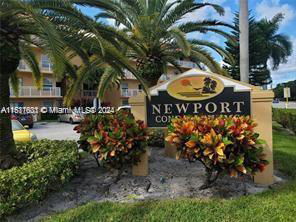 Front view of a multi-story building with palm trees and a sign that reads Newport Condominiums.