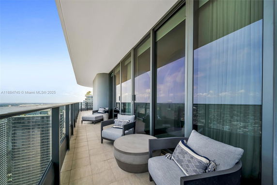 Panoramic view from a high-rise building balcony with seating and glass railing.