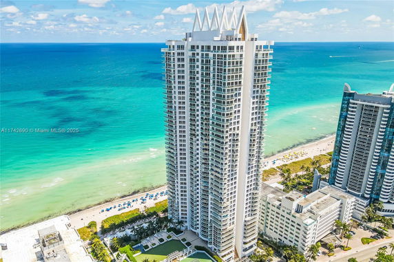 Aerial view of a beachfront skyscraper with ocean in the background.