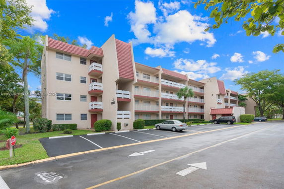 Front view of a multi-story residential building with balconies and a parking area.
