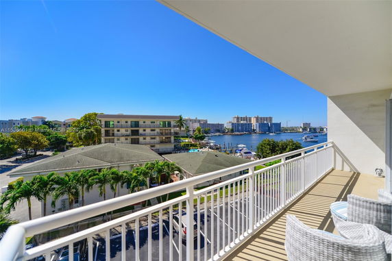 View from a balcony overlooking neighboring buildings and a waterway with boats.