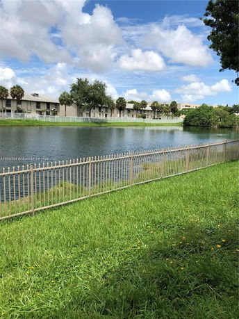 View of a pond with residential buildings in the background.