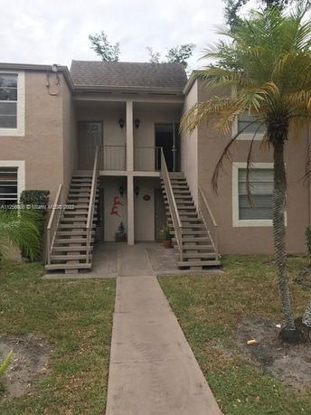 Front view of a two-story building with exterior stairs leading to upper entrances.
