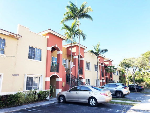 Front view of a multi-story residential building with arches and stairs.