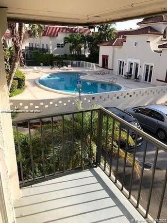 View of a swimming pool with surrounding deck area and adjacent buildings.
