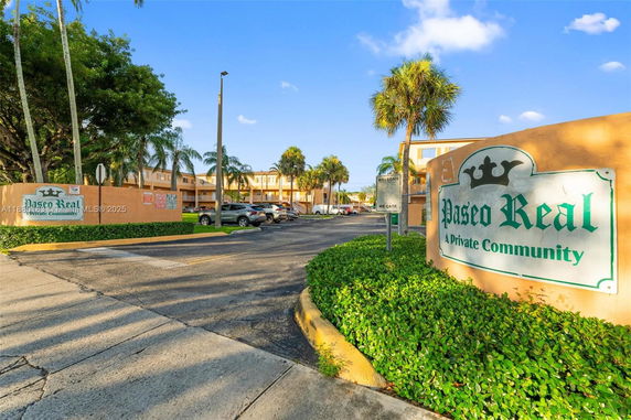 Entrance view of a private community with a sign for Paseo Real and surrounding apartments.