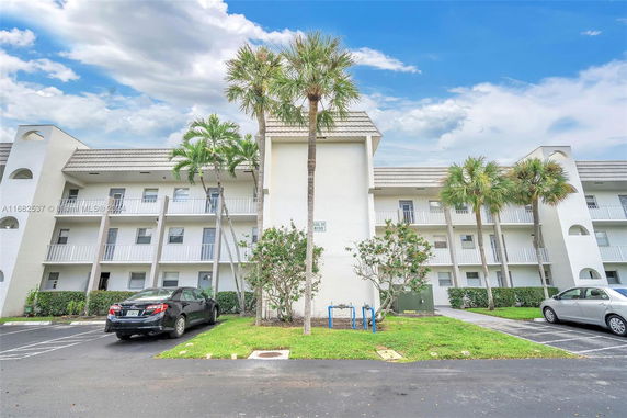 Front view of a multi-story apartment building with balconies and parking area.